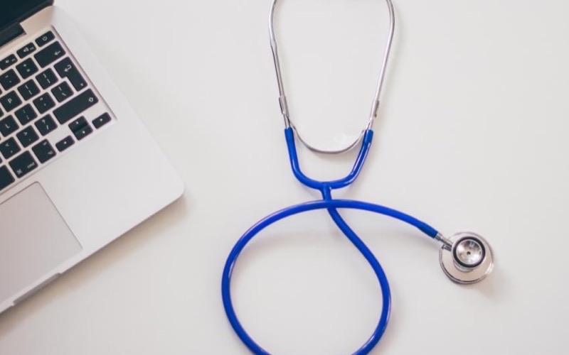 A stethoscope next to a laptop